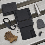 The Full Game Chair folded flat beside a travel mug, keys, gloves and a knit hat on a bleacher plank